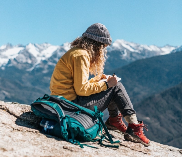 a girl on the mountain writing a travel blog
